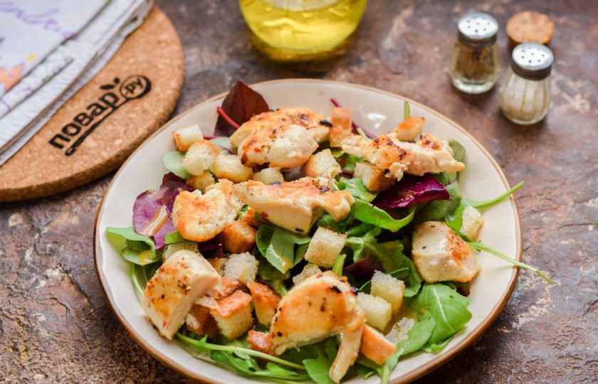 1. Этап. Салат Цезарь от Гордона Рамзи: Выложите кусочки курицы и сухарики.