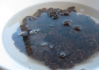 1. Этап. Вкусная запеканка из творога с манкой: 1. Запарьте изюм. Для этого положите его в миску и залейте кипятком. Следите, чтобы вода покрывала сухофрукты полностью. Оставьте его на 3-4 часа. Слейте воду. Хорошо промокните изюм бумажным полотенцем. Переложите в сухую посуду.