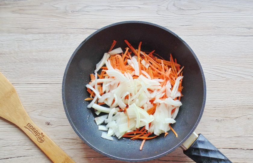 1. Этап. Фунчоза с древесными грибами: Лук очистите, вымойте и нарежьте полукольцами. Добавьте в сковороду.