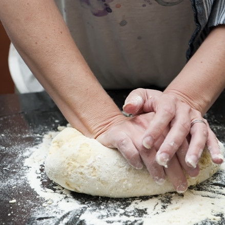 1. Этап. Равиоли с сыром: 6. Выложите тесто из миски на рабочую поверхность, присыпанную мукой. Продолжайте месить руками.