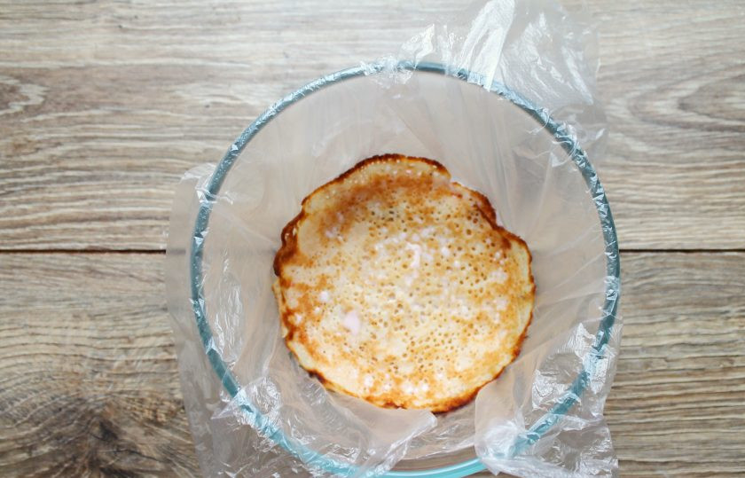 1. Этап. Блинный торт с йогуртовым кремом: Подходящую миску застелите пленкой и налейте на дно немного йогуртовой массы. Сверху выложите блин, немного придавив.