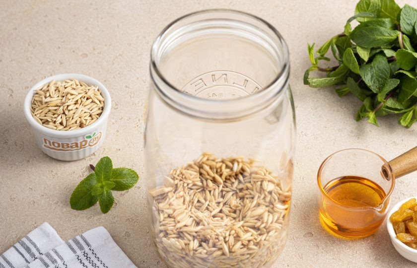 1. Этап. Квас овсяный с медом и изюмом: Переложите промытый овес в банку, добавьте половину от указанного в рецепте меда.