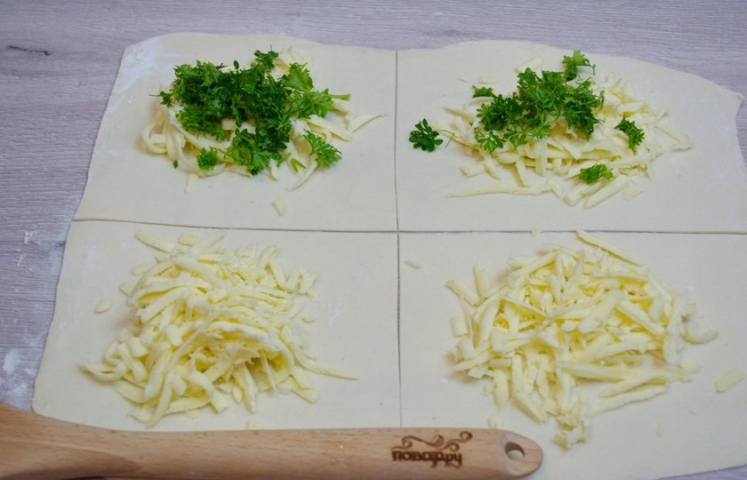 1. Этап. Хачапури из бездрожжевого слоеного теста: На кусочки теста выложите натертый сыр. Слегка его присолите (при необходимости) и поперчите. Измельчите зелень, добавьте её к сыру.