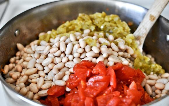 1. Этап. Жаркое из курицы, фасоли и овощей: 4. Добавить куриный бульон, помидоры, белую фасоль и зеленый чили. Добавить соль и перец по вкусу.