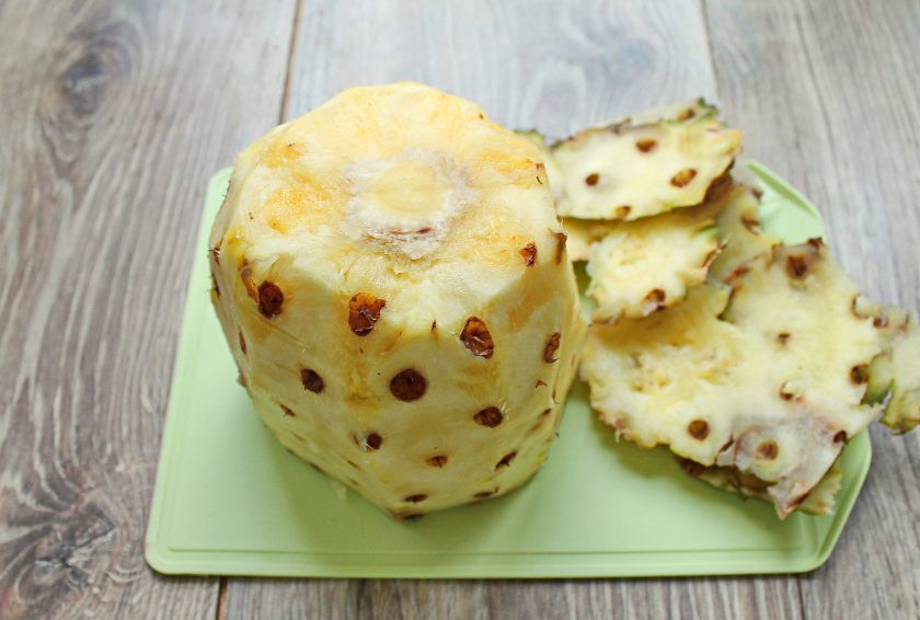 1. Этап. Ананасы на зиму: Ананас тщательно вымойте и обсушите. Срежьте у ананаса верхушку и боковые корки. Вырежьте все вкрапления корки.