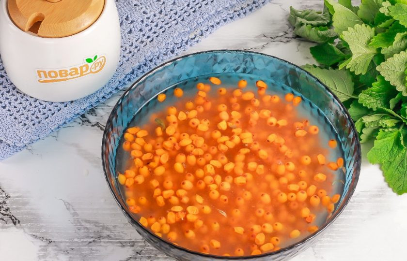 1. Этап. Облепиха без сахара на зиму: Высыпьте ягоды в глубокую емкость и залейте холодной водой. Удалите стебельки, листочки и прочий мусор. Промойте ягоды несколько раз.