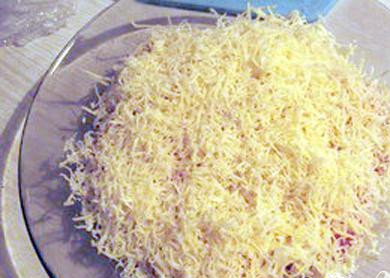 1. Этап. Салат Викинг: 3. возьмите мелкую терку, на которой Вы будете натирать сыр. Делать это можно, непосредственно, над салатницей, либо же в отдельную емкость, а готовое «сырье» уже распределить по салатнику, в котором томятся ранее уложенные ингредиенты. Над блюдом крошить сыр достаточно неудобно, потому как руки довольно быстро устают от монотонной работы и долгого пребывания в подвешенном состоянии. После сыра сделайте слой из чеснока.