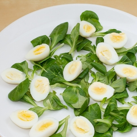 1. Этап. Салат Милые крошки: Перепелиные яйца отвариваем до готовности (2-3 минуты после закипания), остужаем до комнатной температуры, разрезаем пополам и выкладываем на салатные листья.