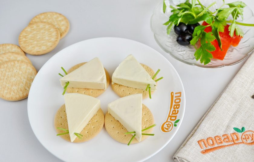 1. Этап. Мышки на крекерах: 2. Ка крекер положите по сырному треугольничку. Из веточек петрушки сделайте усики: просто воткните в сыр небольшой кусочек веточки.