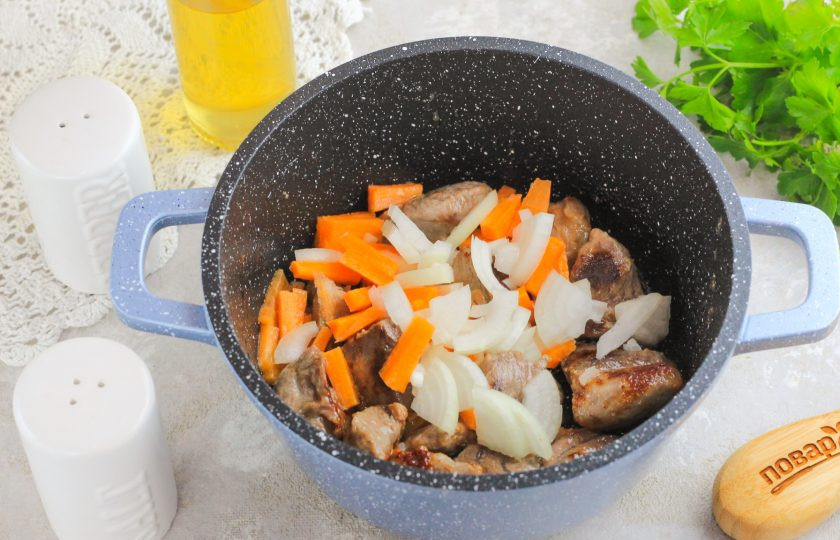 1. Этап. Плов с айвой и говядиной: Нарежьте очищенную морковь брусочками, а лук — полукольцами и добавьте в емкость. Обжарьте 3-5 минут.