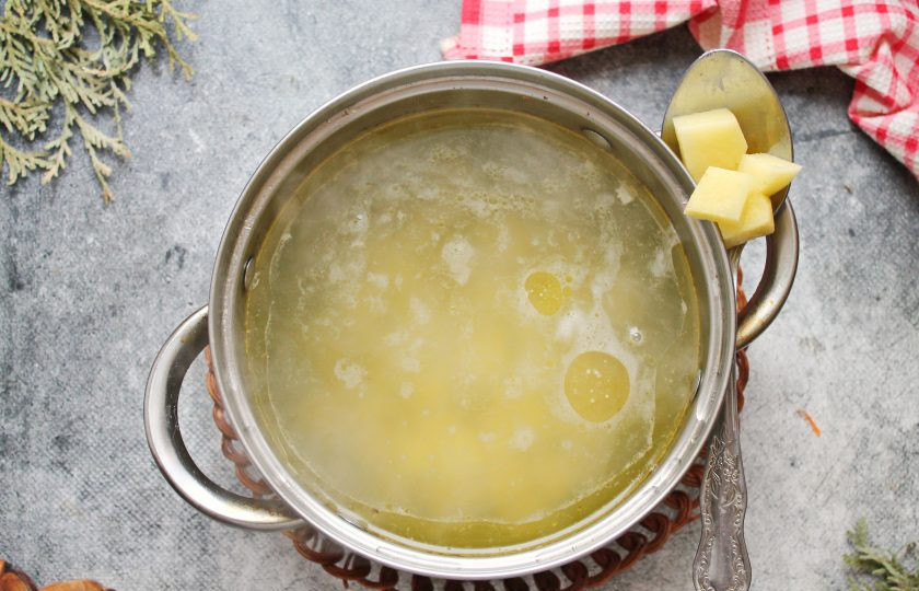 1. Этап. Уха из рыбных голов: Картофель порежьте средним кубиком и выложите в кипящий бульон.