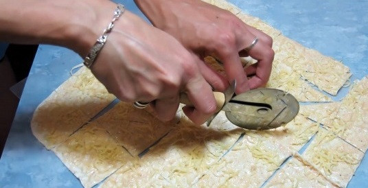 1. Этап. Домашние чипсы из лаваша: 5. Выкладываем лаваш на противень (предварительно смажьте его растительным маслом и застелите пергаментом). Теперь посыпаем тертым сыром и нарезаем специальным ножом.