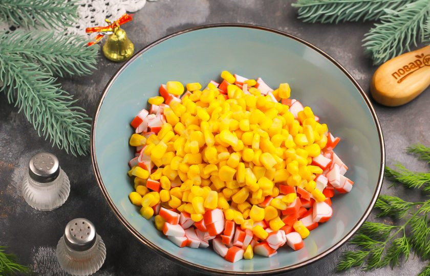 1. Этап. Крабовый салат на Новый год 2025: Вскройте баночку с консервированной кукурузой и слейте маринад. Выложите ее в миску.