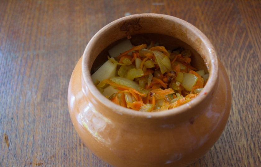 1. Этап. Чанахи с фасолью и грибами: На растительном масле обжарьте нарезанный репчатый лук и морковь. Зажарку выложите в горшочки.