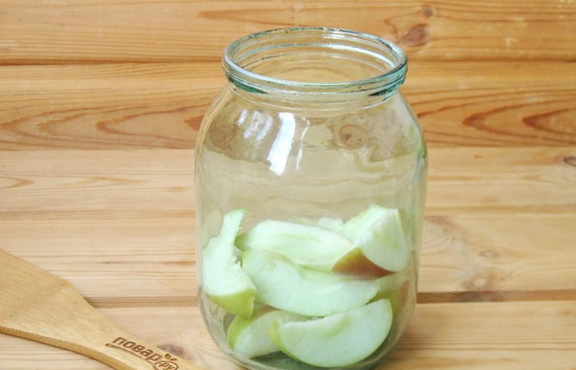 1. Этап. Компот из абрикосов и яблок на зиму: В стерилизованную банку выложите нарезанные дольками яблоки.