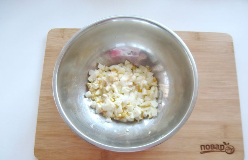 1. Этап. Салат Мошенница: Яйца сварите вкрутую, охладите, очистите и мелко нарежьте. Выложите в миску.