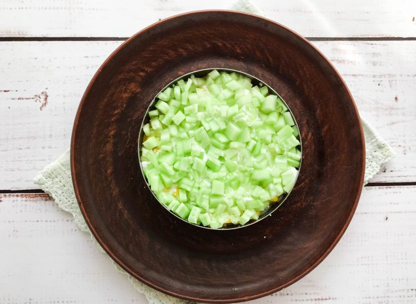 1. Этап. Салат Диана с печенью трески: Огурец помойте под проточной водой, мелко нарежьте и выложите поверх кукурузы. Слой из огурцов смажьте майонезом.