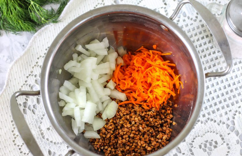 1. Этап. Гречневый суп для ребенка 1 года: Высыпьте промытую гречку в кастрюлю. Очистите морковь и луковицу от шелухи, промойте и натрите в емкость морковь, а лук нарежьте мелкими кубиками и добавьте туда же.