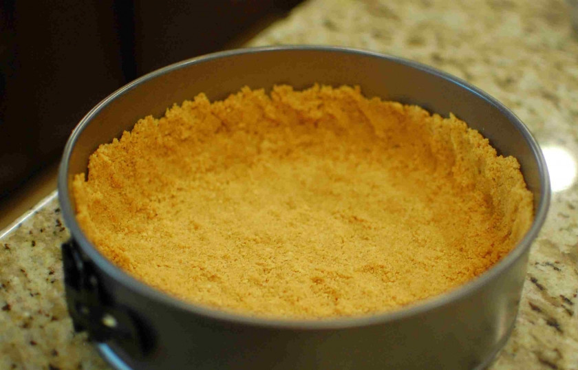 1. Этап. Итальянский пирог с сыром: Потолчите крекерную крошку, перемешайте с сахаром и размягченным сливочным маслом. Вминаем полученную массу в форму для выпекания.