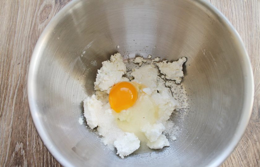 1. Этап. Творожный пирог с брусникой: В миску выложите творог, всыпьте сахар и разбейте туда яйцо. Все хорошенько взбейте до однородной массы.