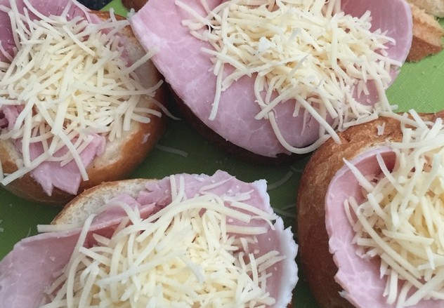 1. Этап. Горячие булочки с яйцом, сыром и ветчиной на завтрак: Присыпаем яйца тертым сыром. Добавляем специи (по желанию). Перекладываем булочки на противень, запекаем в духовке 7-8 минут, температура — 200 градусов.