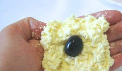 1. Этап. Сыр с чесноком и майонезом: Столовой ложкой набираем небольшое количество массы, формируем из нее лепешку. В середину кладем маслину (по желанию, внутрь маслины можно положить небольшой орех), скатываем все в шарик.