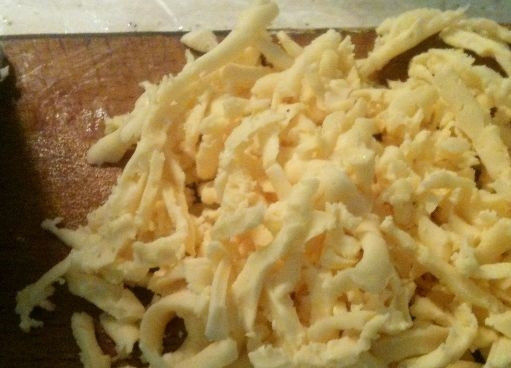 1. Этап. Быстрый луковый пирог: 5. Натрите сыр на крупном полотне терки. Выложите его поверх слоя из жареного лука.