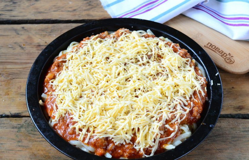 1. Этап. Пирог из спагетти под сыром: Сверху выложите мясную начинку и присыпьте натертым на мелкой терке сыром. Запекайте в духовке 20-25 минут.