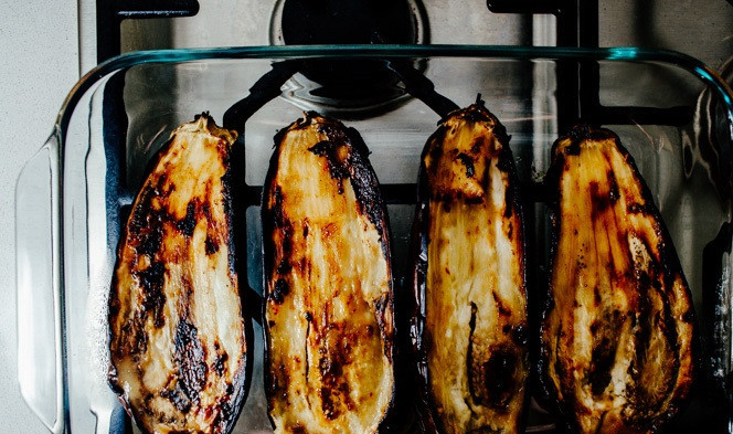 1. Этап. Баклажаны в карамели: 2. Выложить баклажаны мякотью вниз и отправить в разогретую духовку. В зависимости от размера, запекать баклажаны в карамели в домашних условиях от 15 до 25 минут. Вынуть их из духовки и переложить в жаропрочную форму подходящего размера.