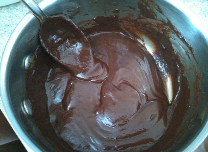 1. Этап. Пирожные Ламингтон, ароматизированные цедрой апельсина: Верните сотейник с глазурью на огонь, дайте содержимому закипеть, продолжая перемешивать ложкой. Дайте готовой шоколадной глазури остыть, периодически перемешивая её во избежание расслаивания.