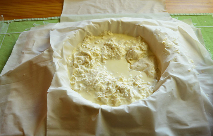 1. Этап. Быстрый пирог с сыром: Начинка – главная часть. Так как консистенция сырной смеси очень жидкая, кусочки слоеного теста нужно в нее макать – именно из них будет формироваться пирог. Используйте столько кусочков теста, сколько понадобится. Делайте это максимально быстро. Остатками смеси залейте полученную слоено-сырную массу.