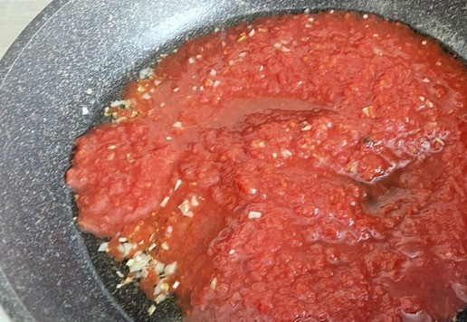 1. Этап. Паста с помидорами и тунцом: В глубокой сковороде разогрейте оливковое масло, добавьте рубленый чеснок, прогрейте все вместе 30–40 секунд. Следите за тем, чтобы чеснок не подгорел. Добавьте протертые томаты.