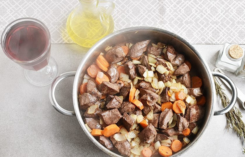 1. Этап. Мясо в вине: Выложите первую часть овощей к поджаренному мясу и перемешайте. Жарьте на среднем огне 5 минут, помешивая.