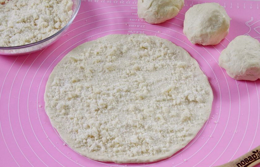 1. Этап. Слойки на кефире: Раскатайте кусочек теста в круг диаметром около 24 см и посыпьте крошкой.