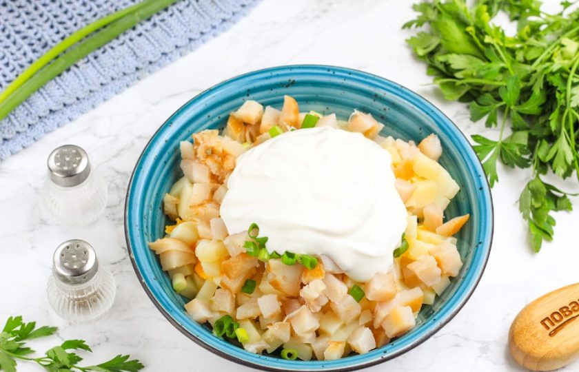 1. Этап. Салат с масляной рыбой: Выложите сметану любой жирности и перемешайте. Если вы будете подавать салат чуть позже, то и заправляйте его только перед подачей. Сметану допустимо заменить майонезом или чесночным соусом любой жирности.