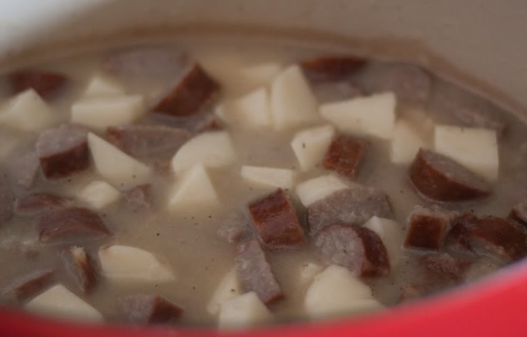 1. Этап. Немецкий суп с колбасками: Добавьте в кастрюлю куриный бульон, картофель, перец и тмин. Хорошенько перемешайте. Затем влейте три стакана воды.