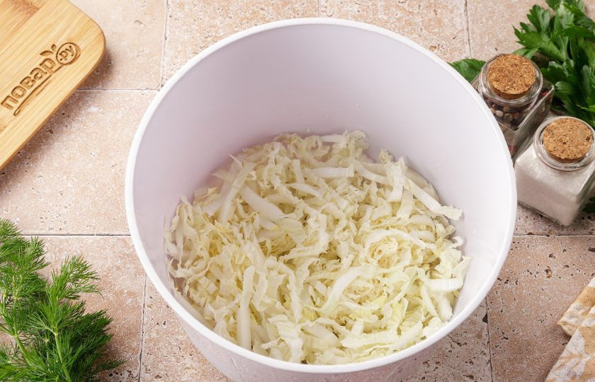 1. Этап. Салат с кальмаром, креветками и огурцом: Пекинскую капусту нашинкуйте соломкой и переложите в глубокую миску.