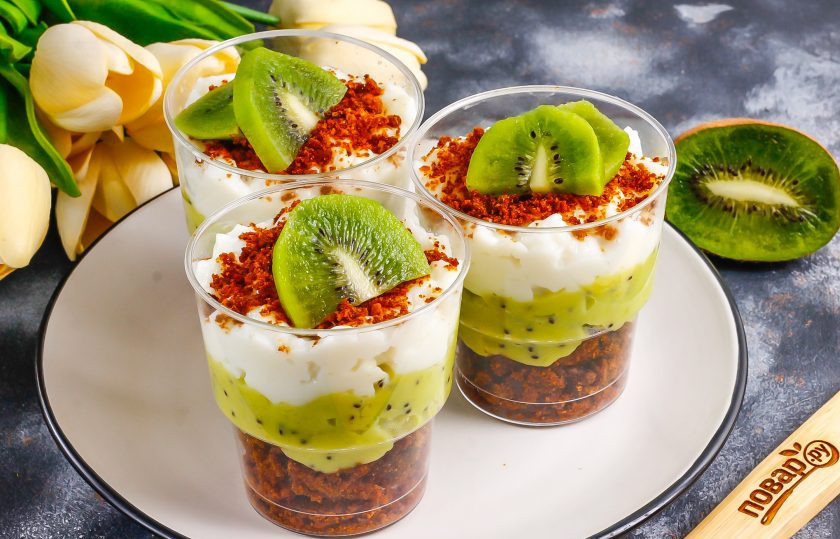 1. Этап. Трайфл с киви: Сметану любой жирности или сливки взбейте с оставшимся сахаром. Если сметана магазинная, то обязательно добавьте загуститель для сметаны. Выложите сметанный крем поверх джема из киви. Присыпьте песочной крошкой и украсьте ломтиками киви. Поместите трайфлы в холодильник минимум на 30 минут для пропитывания.