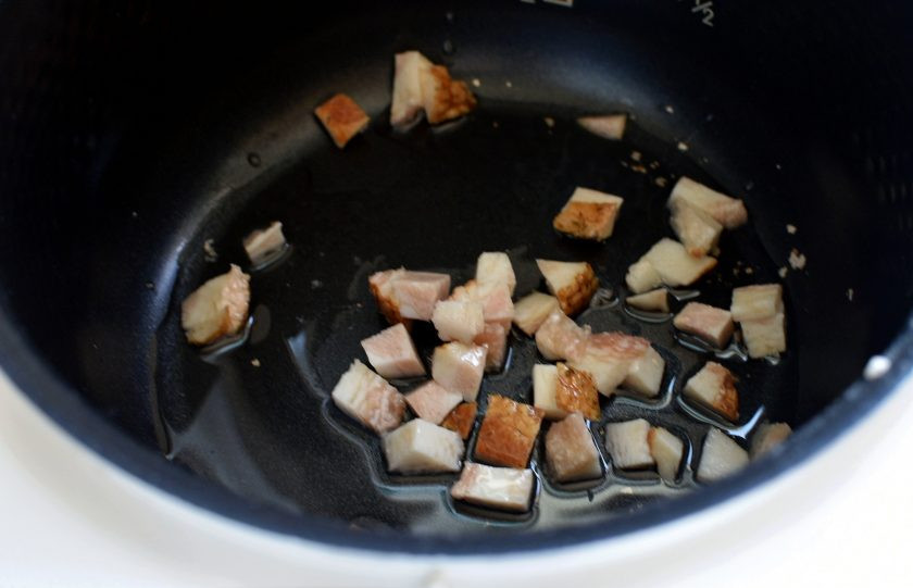 1. Этап. Заячьи потрошки в слоеном тесте: Нарежьте копченую грудинку мелкими кубиками и распустите ее в чаше мультиварки с маслом до прозрачности.
