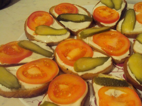 1. Этап. Бутерброды со шпротами и помидорами: Обжаренный батон смазываем майонезом. Сверху выкладываем помидоры и огурцы.