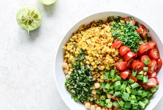 1. Этап. Cалат с нутом: 3. Отправьте в глубокую мисочку нут, кукурузу, помидоры, измельченную зелень. Выжмите сок одного лимона или лайма и полейте.