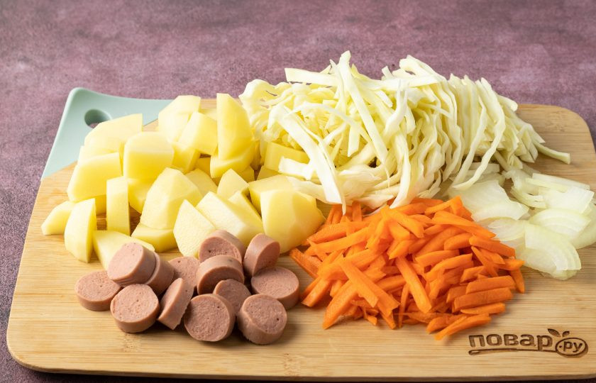 1. Этап. Рагу по-крестьянски: Капусту тонко нашинкуйте. Морковь порежьте брусочками или натрите на крупной терке. Репчатый лук порежьте полукольцами. Картофель очистите и порежьте кубиками среднего размера. Сосиски очистите и порежьте кружочками.
