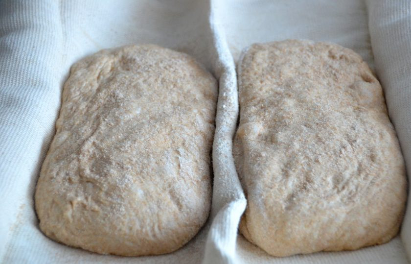 1. Этап. Чиабатта из цельнозерновой муки: Щедро присыпьте мукой салфетку, выложите на нее заготовки чиабатты, подперев с боков валиками из небольших полотенец, сделав между заготовками складку. Дайте тесту 