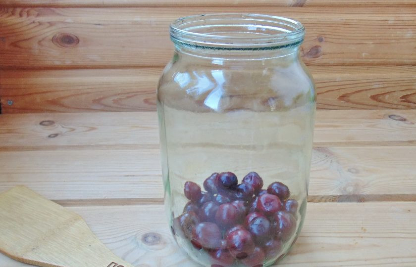 1. Этап. Компот из вишни и абрикосов на зиму: Простерилизуйте банку и выложите в неё вымытую вишню.