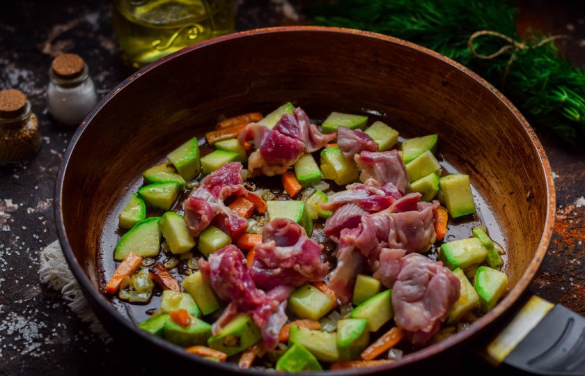 1. Этап. Тушеные куриные желудки с кабачками: Куриные желудки промойте и просушите, нарежьте небольшими кубиками и добавьте в сковороду.
