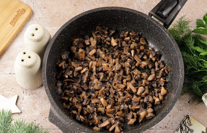 1. Этап. Новогодний салат Варежка на год Змеи: Лук и грибы нарежьте кубиками и обжарьте на растительном масле до готовности. В конце посолите и поперчите по вкусу.