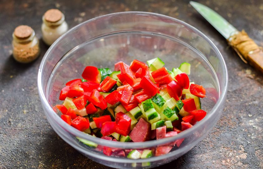 1. Этап. Салат с ананасами и колбасой: Болгарский перец очистите и сполосните, нарежьте небольшими кубиками и добавьте в салат.