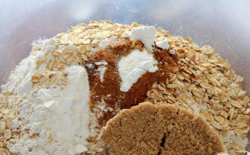 1. Этап. Имбирное печенье с клюквой: 1. Разогреть духовку на 200 градусов. Выстелить противень пергаментной бумагой и отложить в сторону. Нарезать сливочное масло на куски. В большой миске смешать муку, овсяные хлопья, сахар, имбирь, корицу, гвоздику, соль, разрыхлитель и соду.