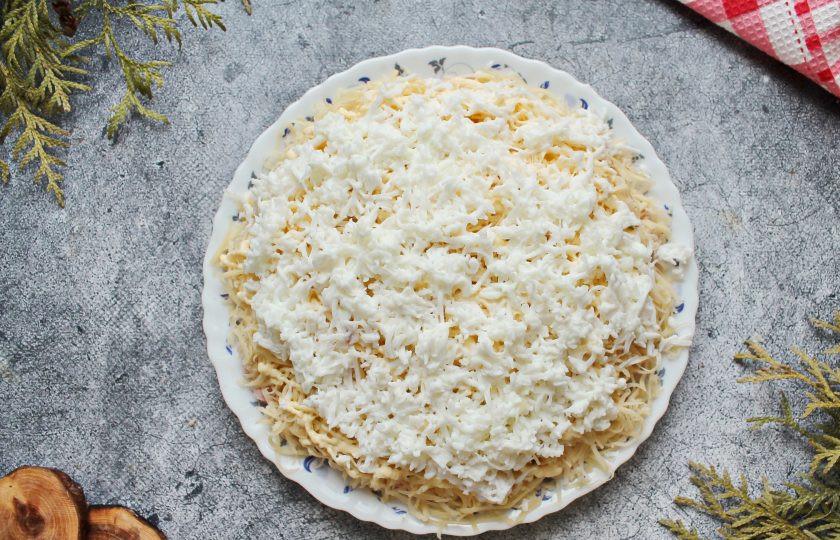 1. Этап. Салат Орхидея с чипсами и ветчиной: Вареные яйца очистите и разделите на белки и желтки. Белки натрите на средней терке и посыпьте поверх сырного слоя. Уберите салат на 20 минут в холодильник, чтобы он настоялся.