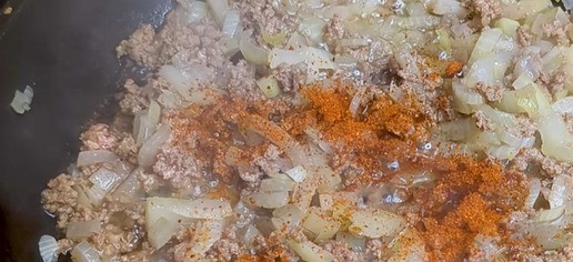 1. Этап. Запеканка из тыквы с мясной начинкой: На сковороде разогрейте масло и обжарьте мелко нарезанный лук до золотистого цвета. Добавьте 300 г фарша, соль, чёрный перец и паприку, хорошо перемешайте. Готовьте на среднем огне, пока фарш не прожарится.
